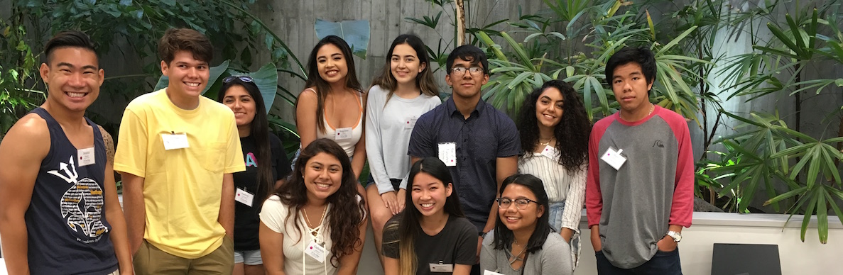 Group of 11 students standing in two rows, smiling for the camera